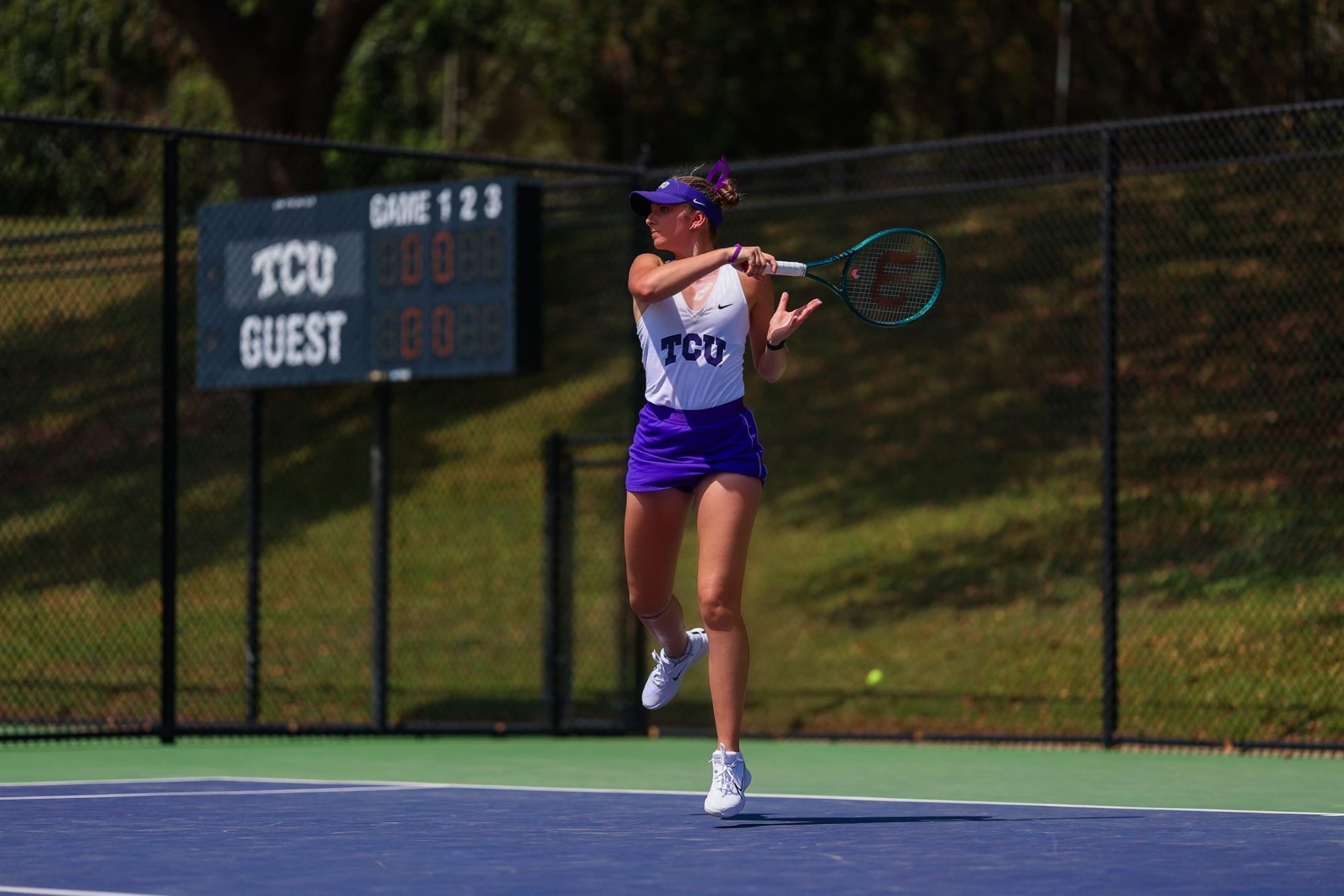 Tomi Main serving during a TCU tennis match