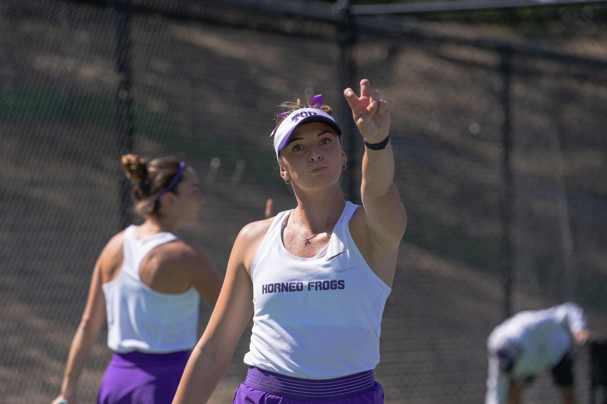 Tomi Main pointing during a doubles match at TCU, showing leadership and communication