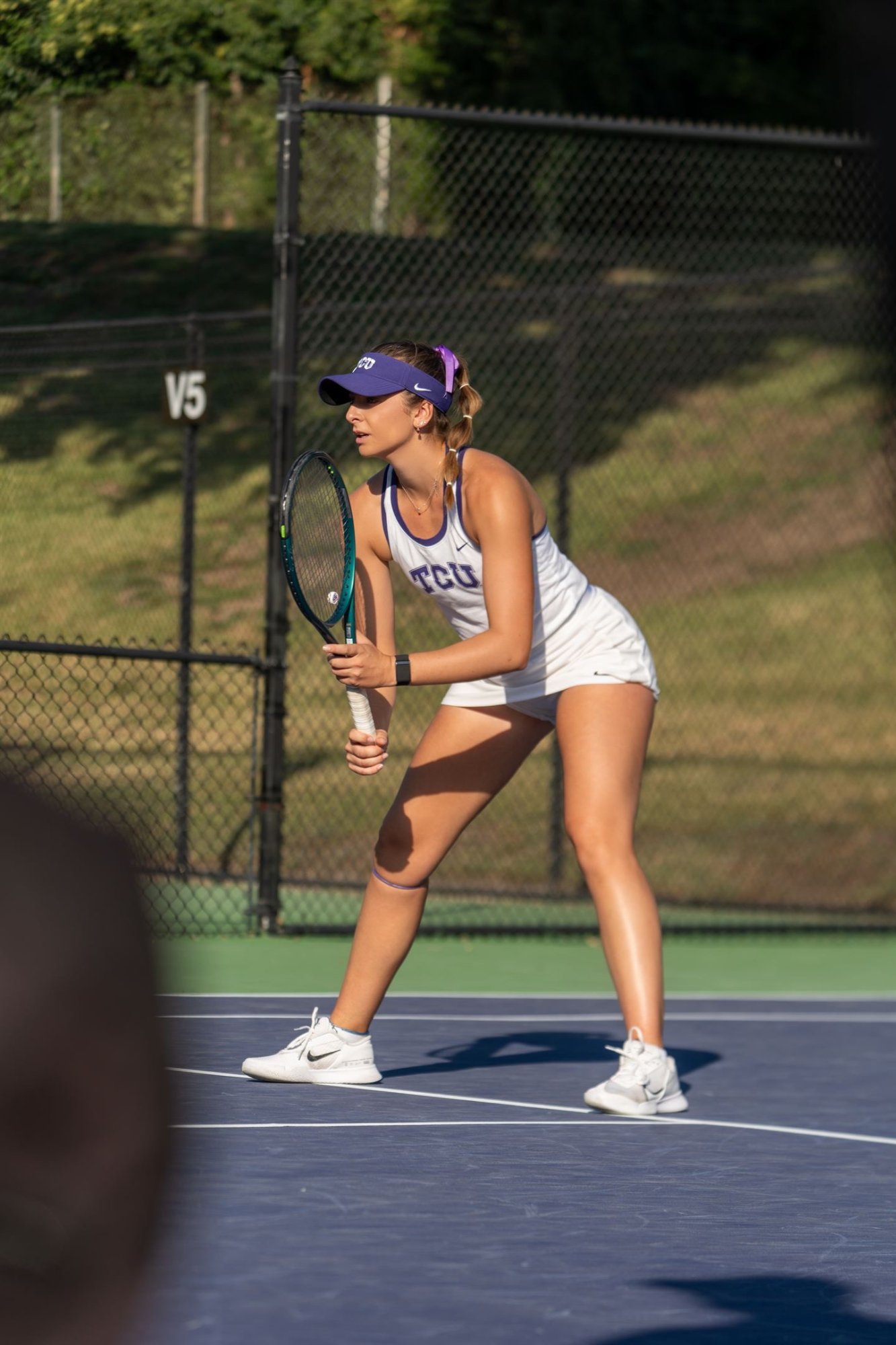 Tomi Main competing for TCU Horned Frogs in purple visor and uniform, ready position on court