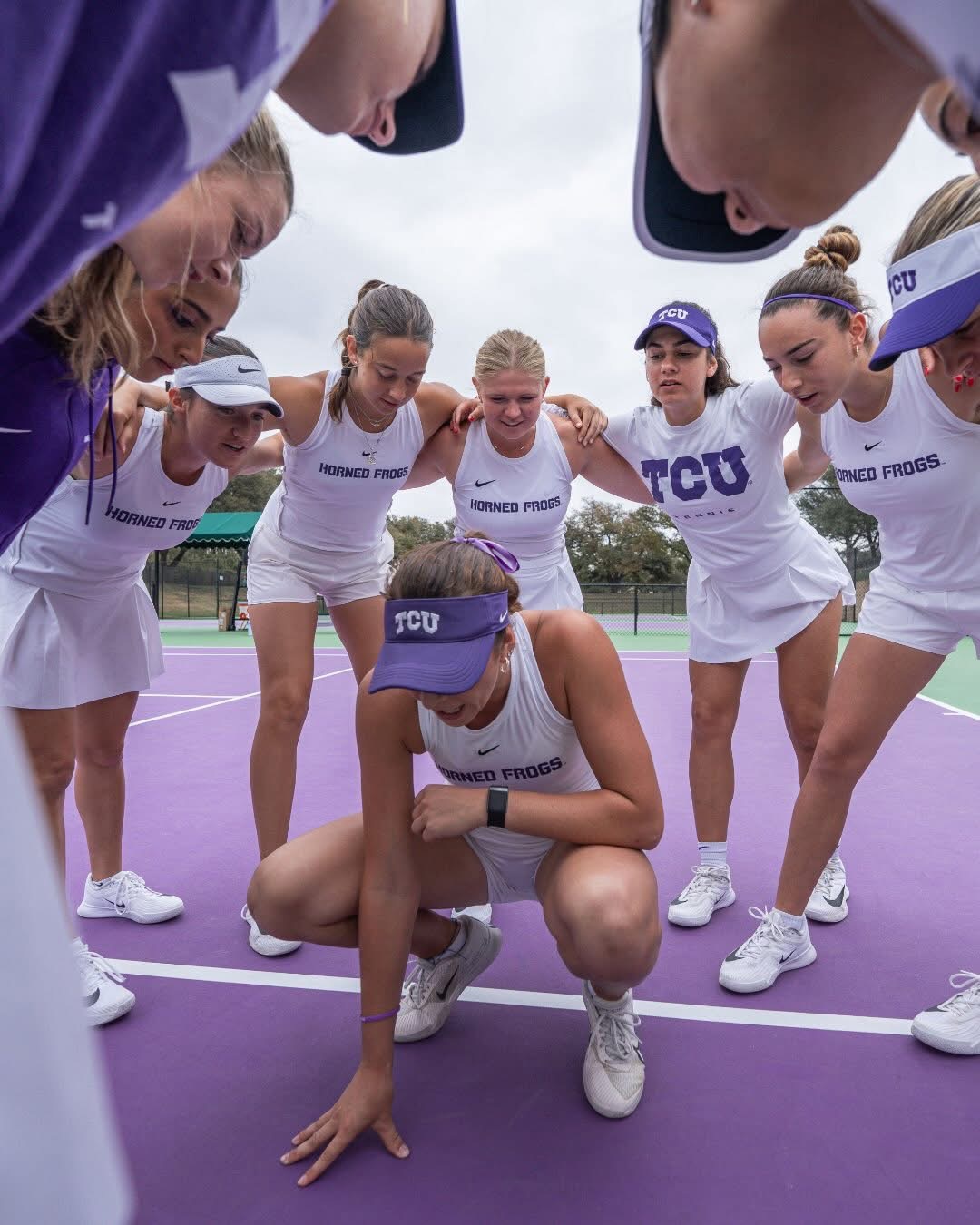 Tomi Main competing for TCU Horned Frogs in purple visor and uniform, ready position on court